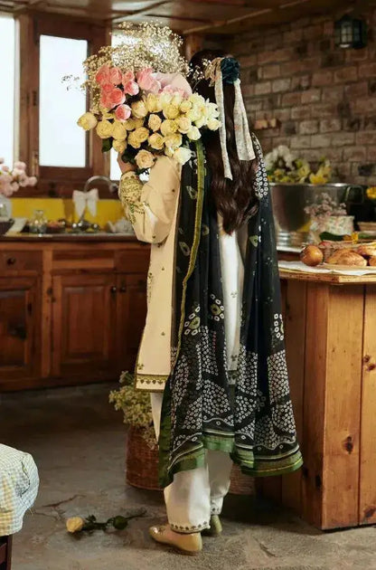 Woman in elegant white outfit holding a floral bouquet, showcasing winter wedding collection in a cozy kitchen setting.