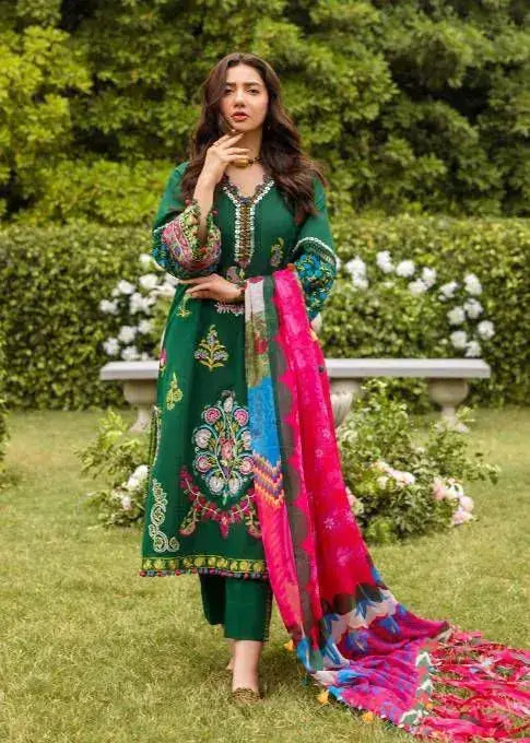 Elegant model in green embroidered dress with colorful shawl in a garden setting, showcasing winter wedding fashion.