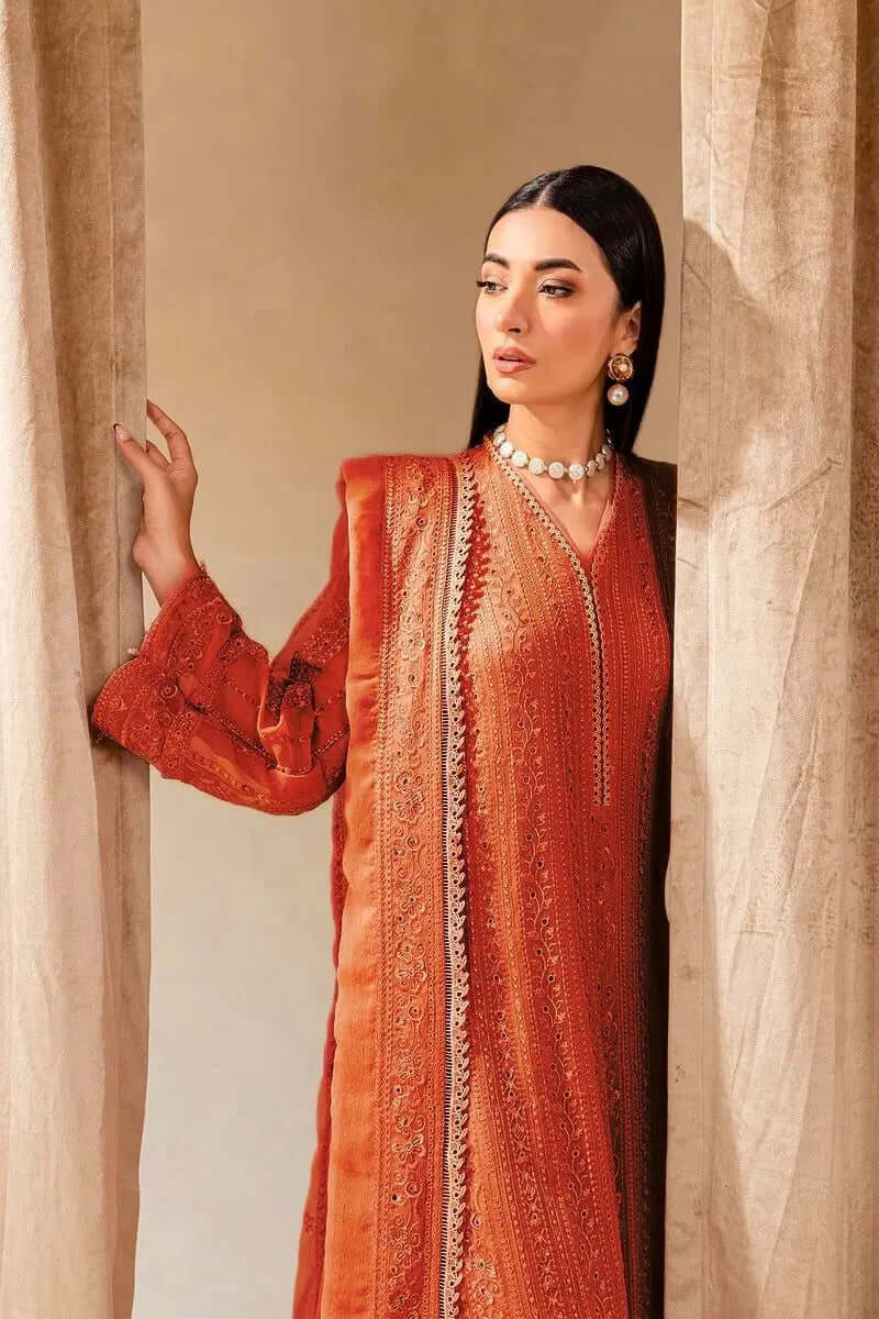 Woman in elegant orange dress with intricate detailing, posing gracefully against a soft backdrop.